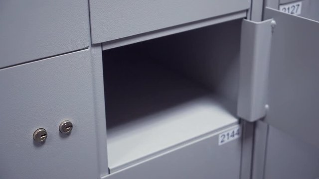 Unrecognisable bank manager hands in white shirt puts two keys into safe depository keyholes to open it