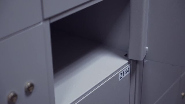 Unrecognisable bank clerk hands in white shirt puts two keys into safe depository keyholes to open it