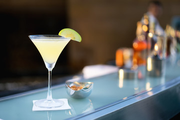 Cocktail alcoolisé apple martini tourné au bar avec flou de barman en arrière-plan.