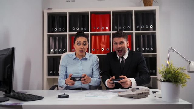 Ywo Business collegues couple man and woman playing videogames with enthusiasm. I do not want to work today concept. Friday evening. No time to job, we want to game now! 4k uhd.