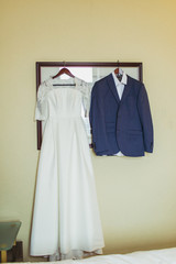 Bride dress and groom suit in dressing room indoors