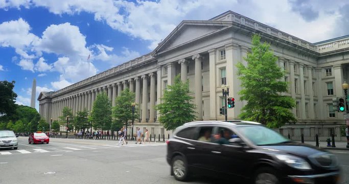 WASHINGTON, D.C. - Circa August, 2017 - A daytime summer establishing shot of the US Treasury Department on Pennsylvania Avenue in DC. The Washington Monument is in the background.  	