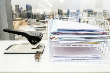 business documents stack in box with big paper punch in office
