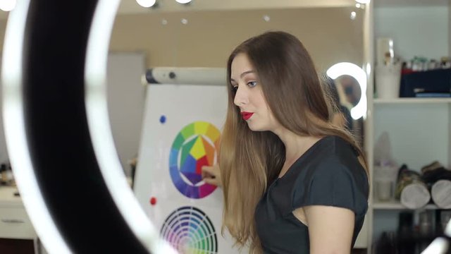 Master class of make-up. The girl shows how to mix colors on the color range of Itten.