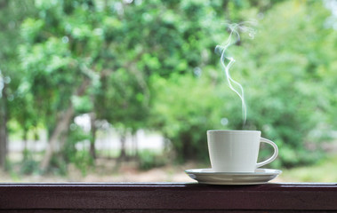 white cup of hot coffee on green natural background