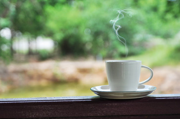 white cup of hot coffee on green natural background