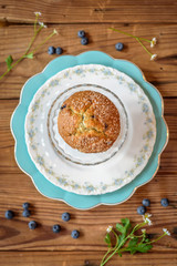 Overhead food shot of blueberry muffin on china plate with chamomile garnish