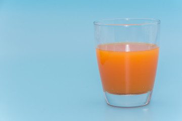 a cup of orange juice on Light blue background