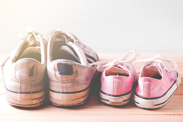 Pink girl sneakers and White man sneakers on a wooden floor and white background with copy space