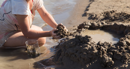 Girl playing in the sand on the lake