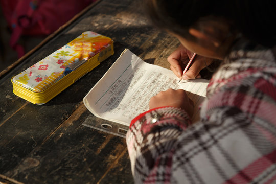 Schoolgirl writing at desk in classroom