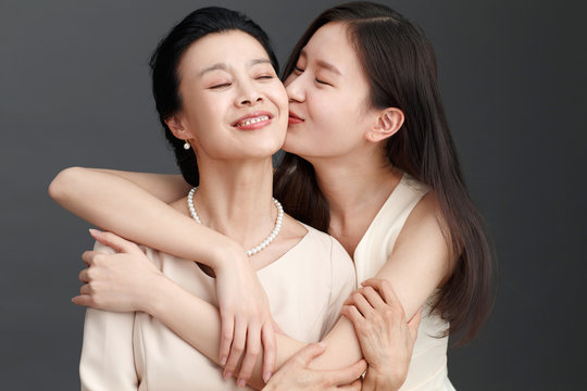 Studio shot of young woman kissing mother