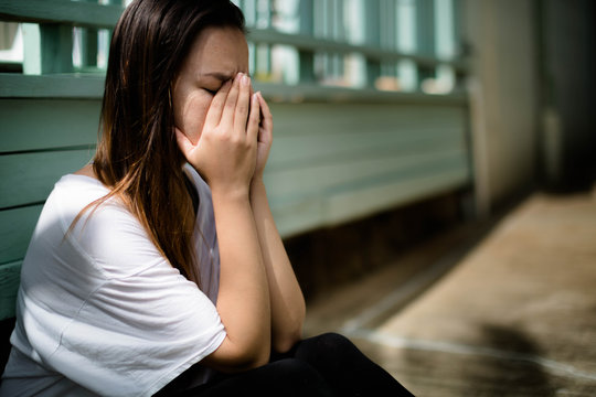 Depressed woman sitting with her hands covering her face overwhelmed with emotion