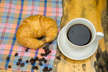 Cups of coffee and croissants On an old wooden floor, leaf background