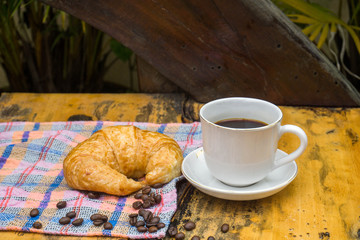 Cups of coffee and croissants On an old wooden floor, leaf background