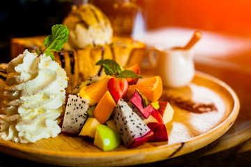 Fruit salad with strawberries, oranges, apples and Dragon fruit 
 on wooden plates with ice cream.selective focus