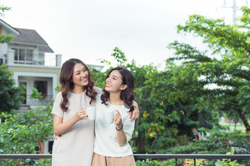 Happy young women friends well-dressed smiling while standing together