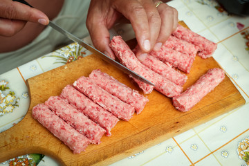 Detail of raw meat rolls on chopping board.