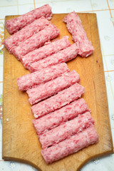 Detail of raw meat rolls on chopping board.