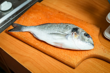 Detail of a raw bream fish on chopping board.