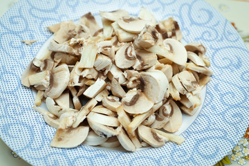 Detail of chopped champignons on a plate on kitchen table.