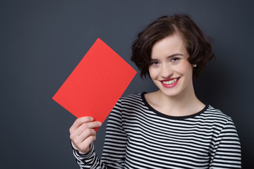 glückliche frau versteckt ihr gesicht hinter einer leeren seite