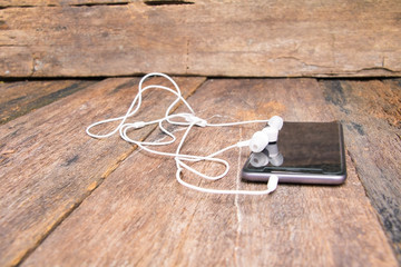 white earphone on mobile phone with table old wooden vintage background and copy space select focus with shallow depth of field