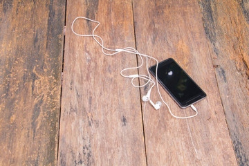 white earphone and mobile phone on table old wooden vintage background with copy space. top view