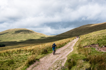 Fototapeta na wymiar Mountain biking in the Brecon Beacons - lone rider climbing towards The Gap