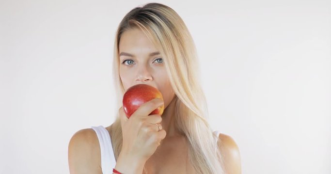 Attractive woman in shirt eating red apple isolated on white background with sound