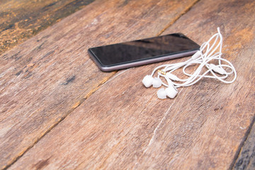 white earphone on mobile phone with table old wooden vintage background and copy space select focus with shallow depth of field