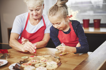 Grandchild with grandma decorating cookies with icing