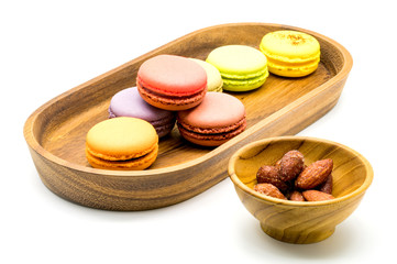Sweet macarons in wooden tray and almonds in wooden bowl