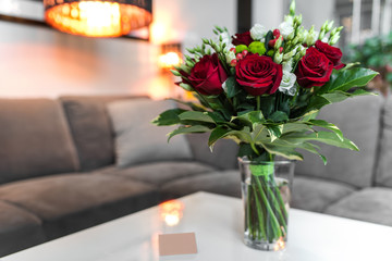Bouquet of red roses in glass standing on the white table in saloon