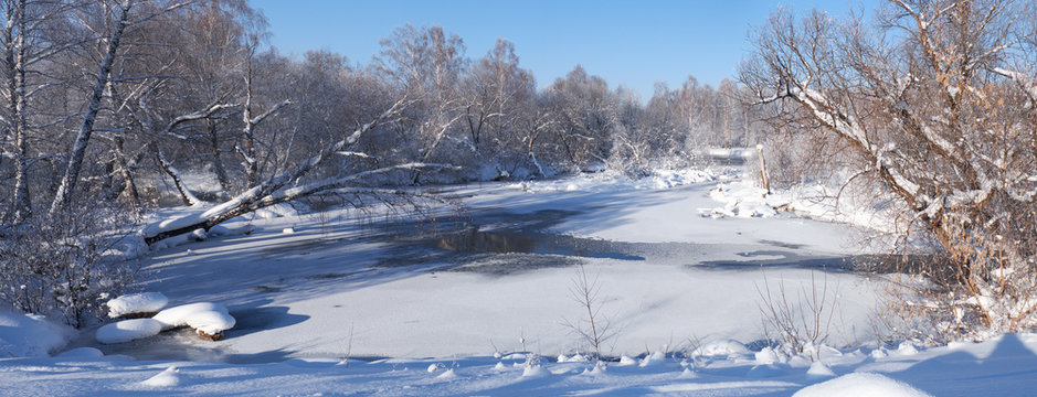 River Koksha surrounded by trees under hoarfrost and snow in Altai region in winter season