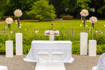 Scenery of the wedding ceremony in the park. White frame decorated with flowers. Ceremony in white style