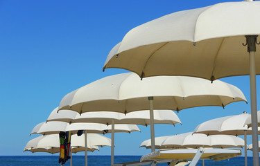 Fototapeta na wymiar Umbrellas and gazebos on Italian sandy beaches. Adriatic coast. Emilia Romagna region