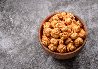 Caramel popcorn in a wooden bowl isolated on stone background