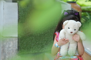 Small beautiful asian girl embraces an amusing bear cub against summer nature, a little girl try to be a model © tpap8228