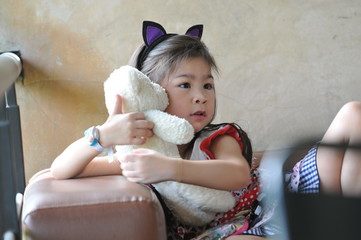 Small beautiful asian girl embraces an amusing bear cub against summer nature, a little girl try to be a model © tpap8228
