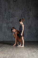 Young ballerina posing with the ballet teacher in studio