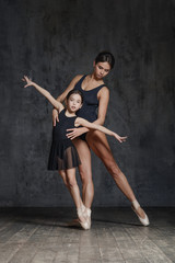 Young ballerina posing with the ballet teacher in studio