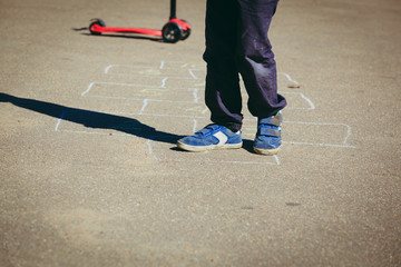 Fototapeta na wymiar little boy playing hopscotch on playground