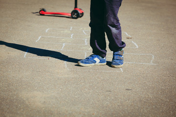 little boy playing hopscotch on playground