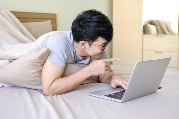 Young man is watching football match premier league online on his bed funny after tried from work all day,relax time ,soft focus background