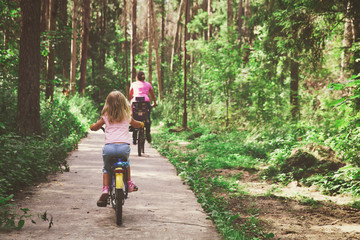 family riding bikes in summer nature