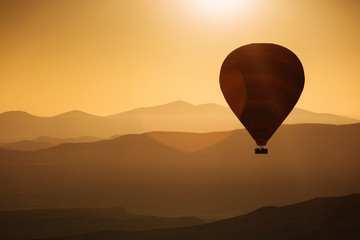 Silhouette of balloons with sunrise in background, aerial view