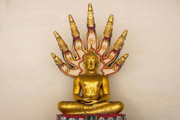 Golden buddha statue in sitting posture with nagas come out from his back