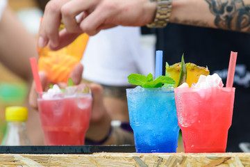 different cold fresh summer cocktails with straws on the wooden board outdoors, selective focus