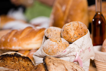 on the foreground a traditional round artisan wheat bread loaves in a basket . And on the background another breads. Rustic style, selective focus